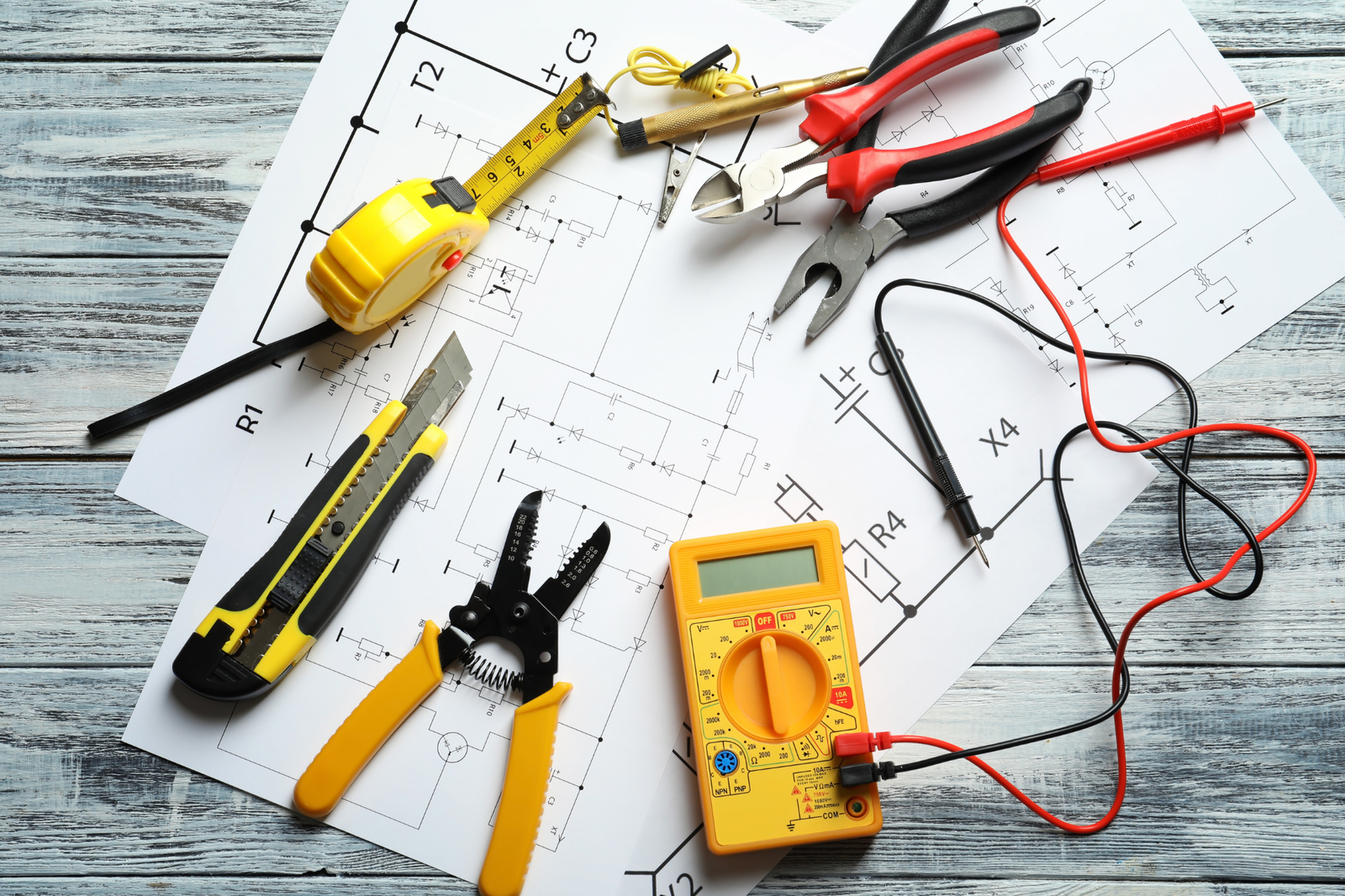 Assortment of tools including spanner, compass, stanley knife and measuring table spread across pages of graphs and maps