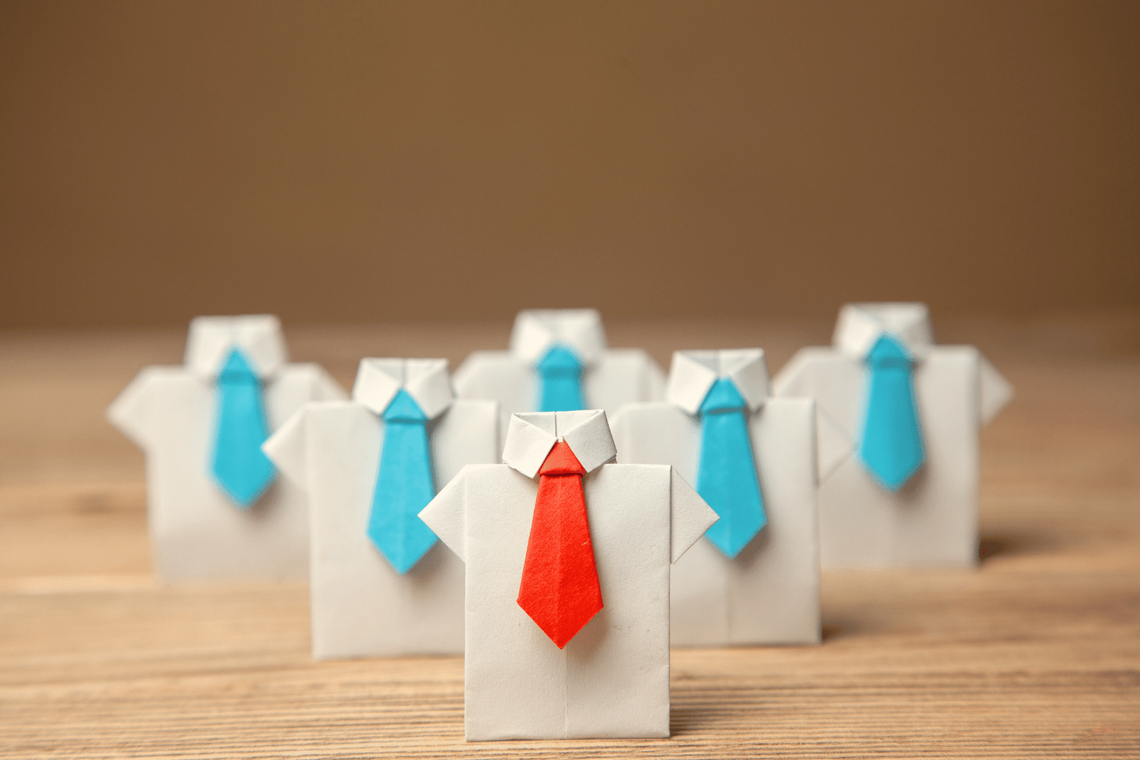 Photo of a series of shirts with blue ties, one shirt with a red tie at the front